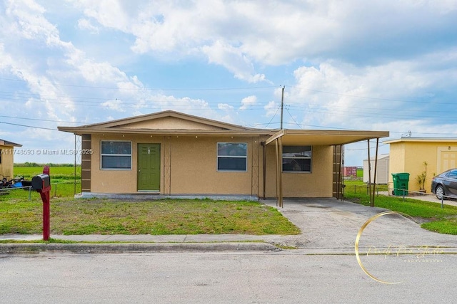 view of front of property featuring stucco siding, a front yard, fence, an attached carport, and driveway