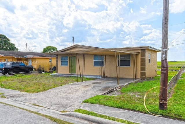 ranch-style house with concrete driveway, a front lawn, fence, and stucco siding