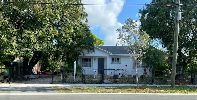 view of front facade with a shingled roof, a fenced front yard, and stucco siding