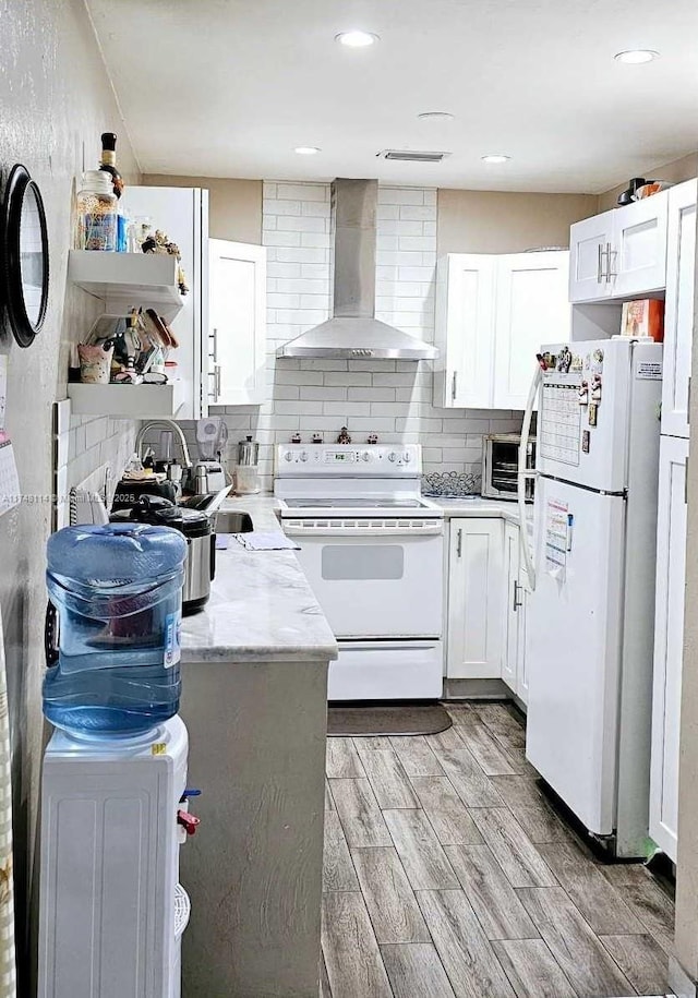 kitchen featuring wood finish floors, white appliances, tasteful backsplash, and wall chimney exhaust hood