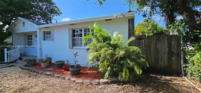 view of side of property with fence and stucco siding