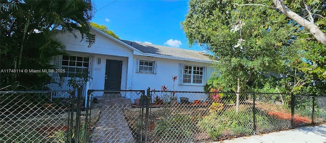 bungalow with a gate, stucco siding, and a fenced front yard