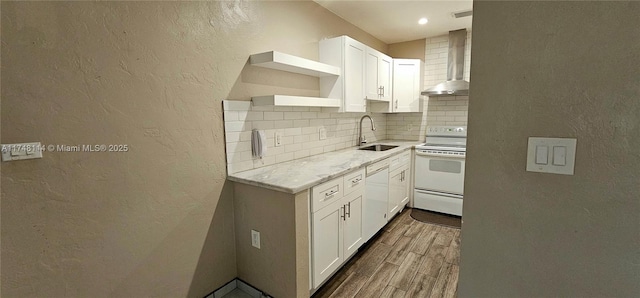 kitchen featuring wall chimney range hood, a textured wall, white appliances, and a sink