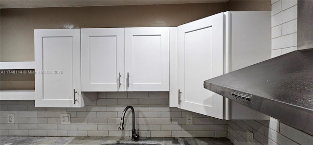 kitchen featuring white cabinetry, backsplash, and a sink