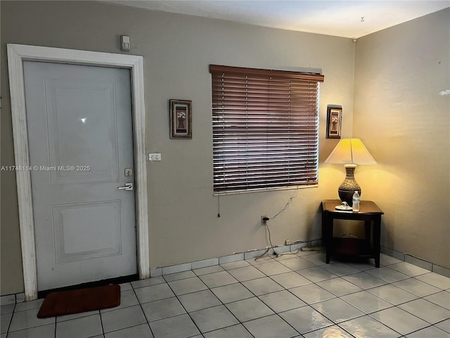 foyer entrance with light tile patterned flooring, a wood stove, and baseboards