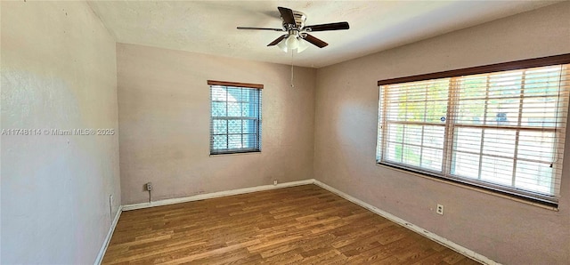 empty room with a ceiling fan, wood finished floors, and baseboards