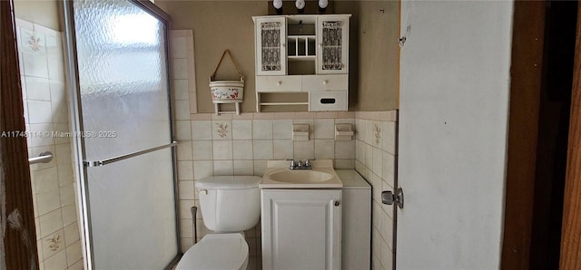bathroom featuring toilet, vanity, a shower stall, and tile walls