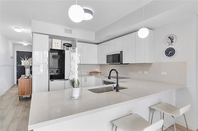 kitchen with a peninsula, white cabinetry, pendant lighting, and light countertops