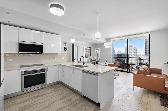 kitchen with light countertops, a peninsula, oven, and pendant lighting