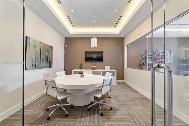 carpeted dining room featuring baseboards, visible vents, and a raised ceiling