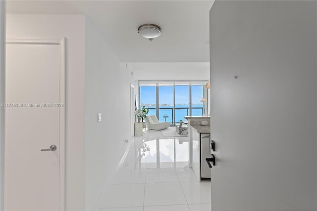 hall with a water view, baseboards, and light tile patterned flooring