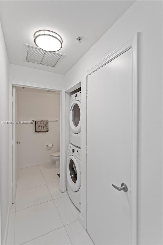 laundry area with light tile patterned floors, visible vents, laundry area, and stacked washer / drying machine