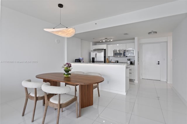 dining space with rail lighting, visible vents, baseboards, and light tile patterned flooring