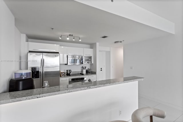 kitchen with light stone counters, stainless steel appliances, visible vents, white cabinetry, and modern cabinets