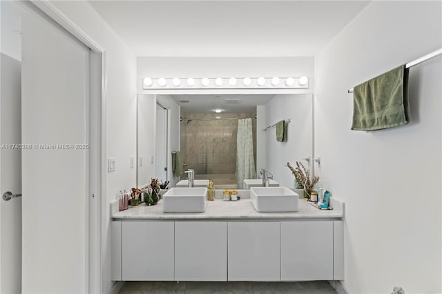 full bathroom featuring double vanity, a sink, and tiled shower