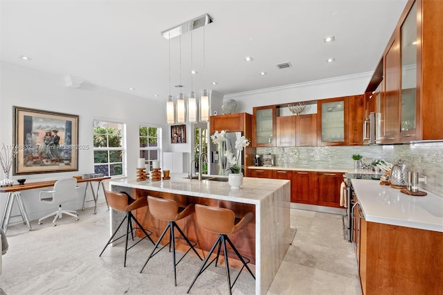 kitchen with visible vents, hanging light fixtures, appliances with stainless steel finishes, an island with sink, and glass insert cabinets