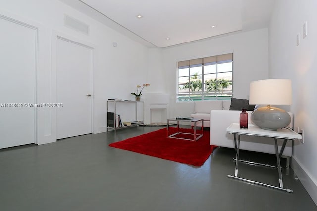 sitting room featuring finished concrete flooring and baseboards