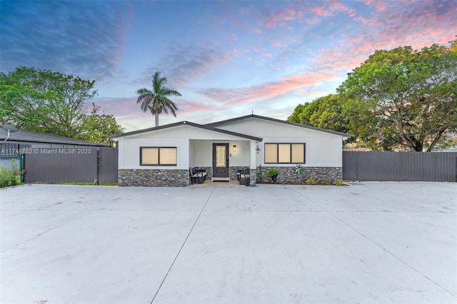 view of front of house featuring stone siding and fence