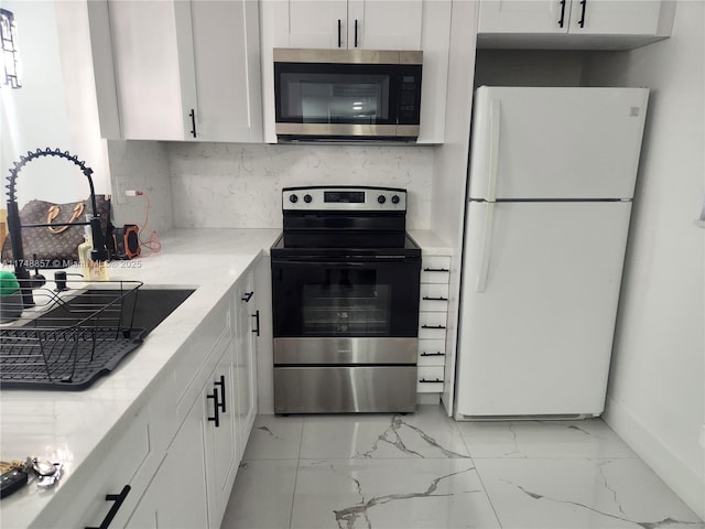 kitchen with white cabinets, appliances with stainless steel finishes, light stone countertops, marble finish floor, and backsplash