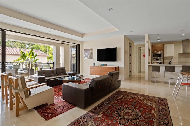 living room featuring baseboards, a raised ceiling, and recessed lighting