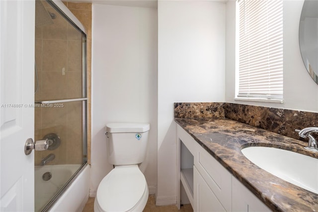 bathroom featuring toilet, combined bath / shower with glass door, and vanity