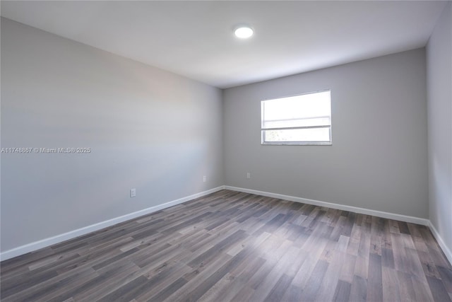 empty room with baseboards and dark wood-style flooring