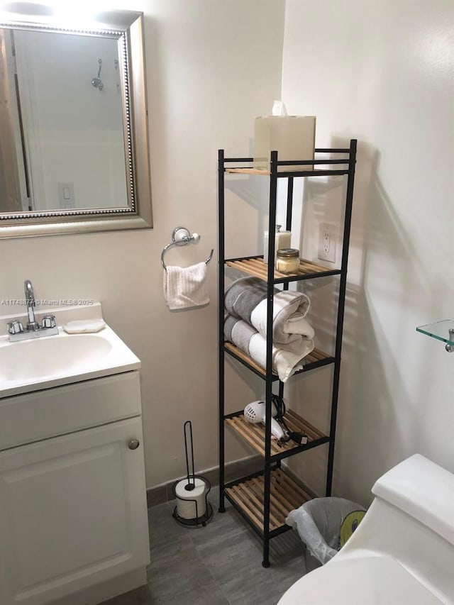 bathroom with toilet, baseboards, and vanity