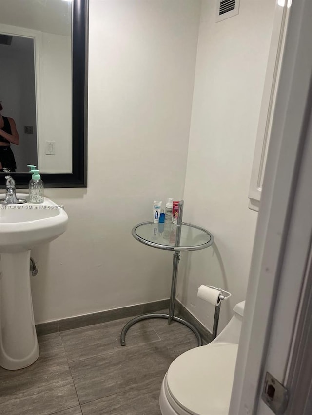 bathroom with toilet, visible vents, and baseboards