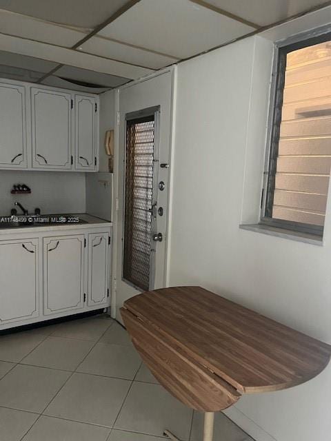 kitchen with plenty of natural light, light tile patterned flooring, a sink, and white cabinetry