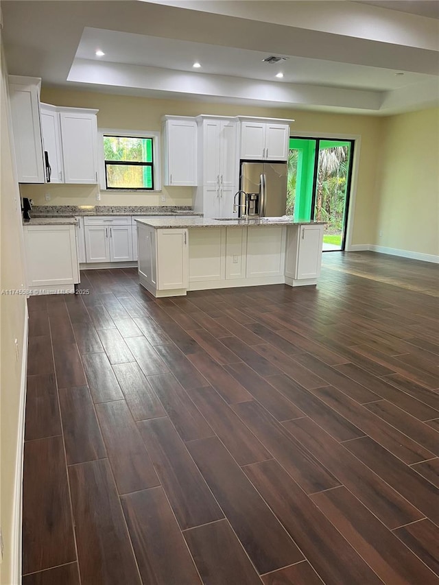 kitchen featuring a healthy amount of sunlight, a tray ceiling, dark wood-style flooring, and stainless steel fridge with ice dispenser