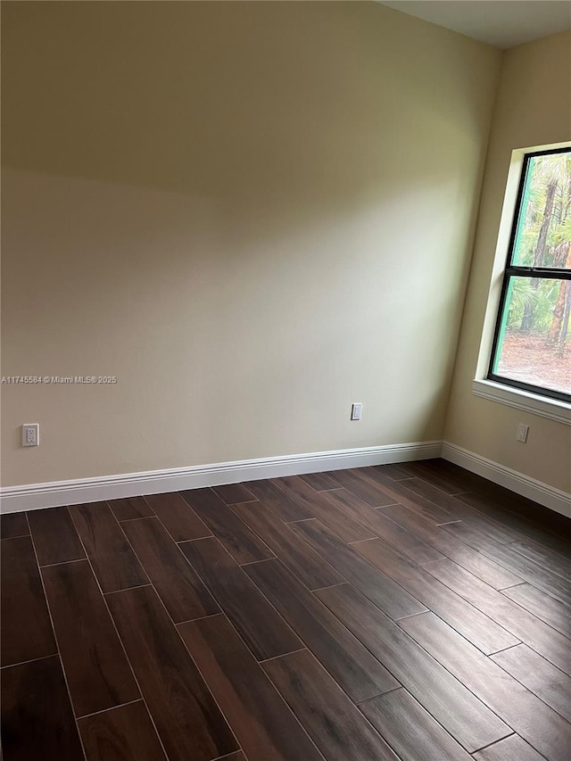 empty room with dark wood-type flooring and baseboards