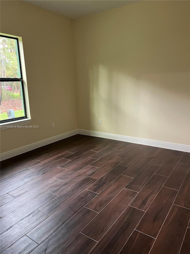 empty room featuring baseboards and dark wood finished floors