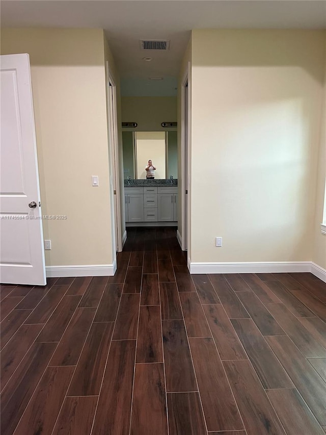 corridor with visible vents, baseboards, and wood finish floors