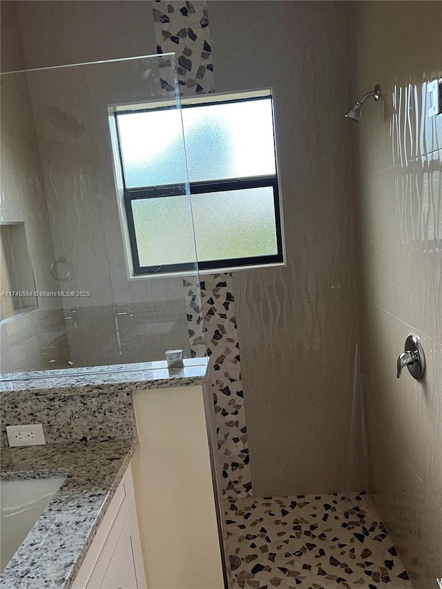 bathroom featuring a walk in shower and vanity