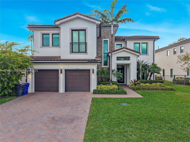 view of front of house featuring a front yard, decorative driveway, fence, and stucco siding