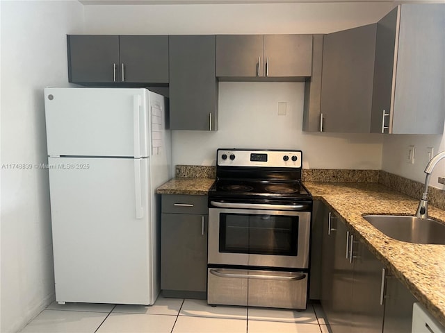 kitchen with dark stone counters, electric stove, freestanding refrigerator, gray cabinets, and a sink