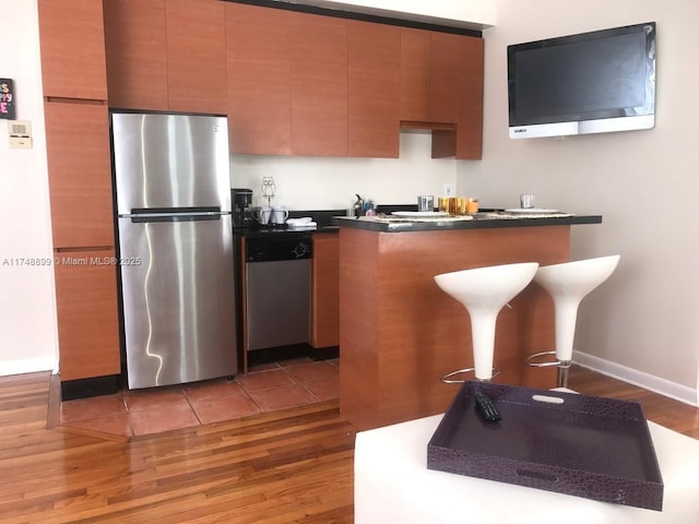 kitchen with dark countertops, light wood finished floors, brown cabinets, and stainless steel appliances