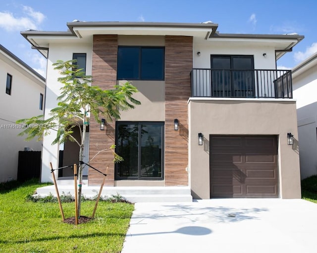 contemporary home with a garage, concrete driveway, a balcony, and stucco siding