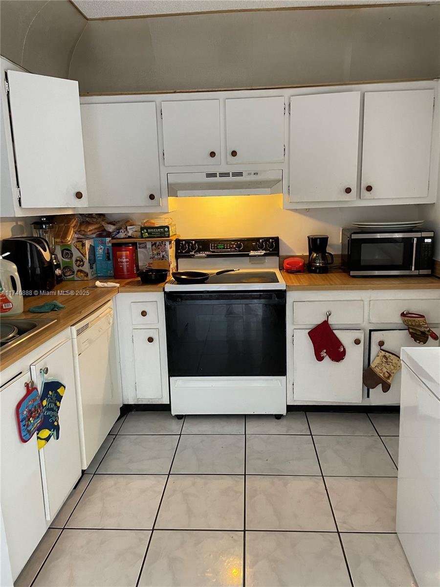 kitchen with electric range, stainless steel microwave, white cabinetry, and under cabinet range hood