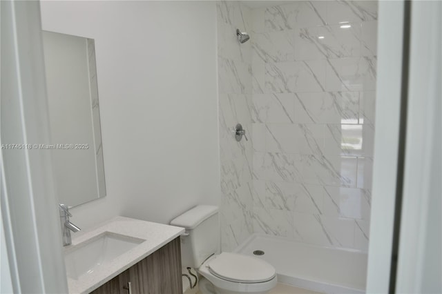 bathroom featuring toilet, a stall shower, and vanity