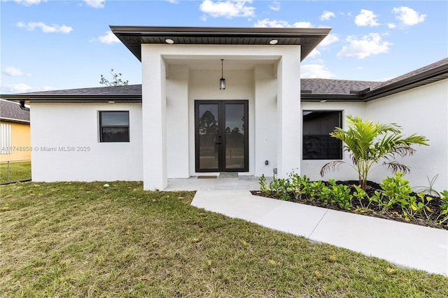 doorway to property with a yard, french doors, a shingled roof, and stucco siding