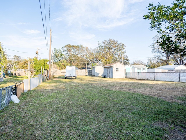 view of yard featuring a storage shed, a fenced backyard, and an outbuilding