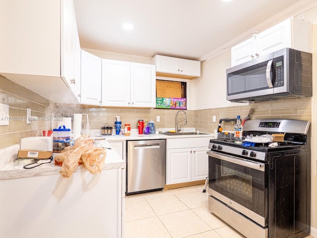 kitchen featuring light tile patterned floors, a sink, white cabinets, light countertops, and appliances with stainless steel finishes