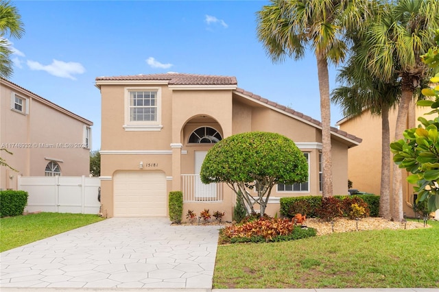 mediterranean / spanish-style home with a garage, concrete driveway, fence, a front lawn, and stucco siding