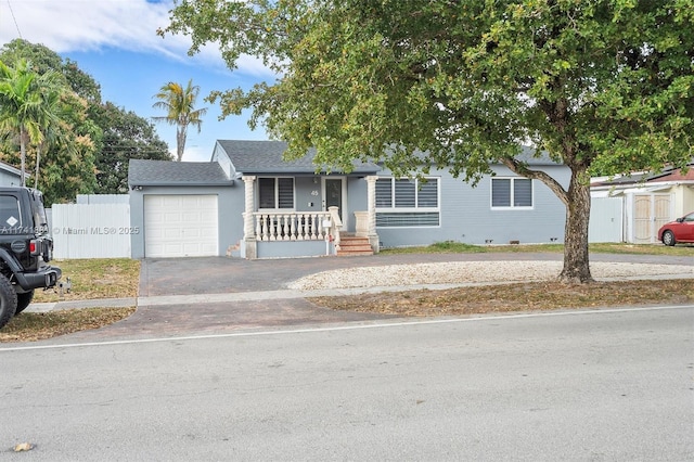 view of front facade with an attached garage, a porch, fence, and aphalt driveway