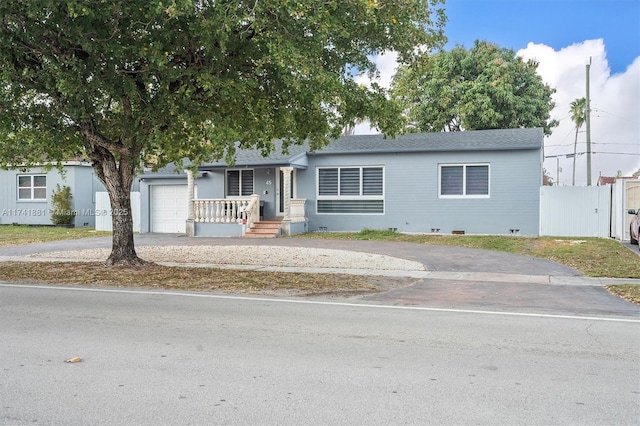 view of front of property featuring driveway, an attached garage, fence, and roof with shingles