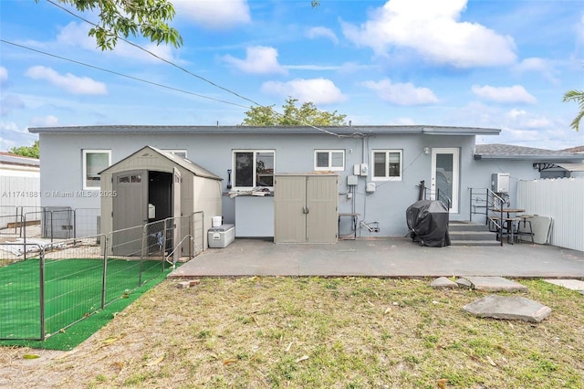 back of house featuring stucco siding, a patio area, fence, and a shed