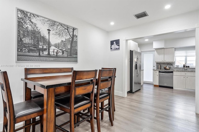 dining space featuring light wood finished floors, baseboards, visible vents, and recessed lighting