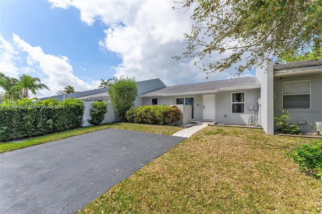 ranch-style home with a front yard, fence, and stucco siding