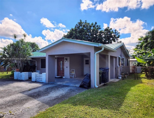 view of front of home featuring stucco siding, fence, metal roof, and a front yard